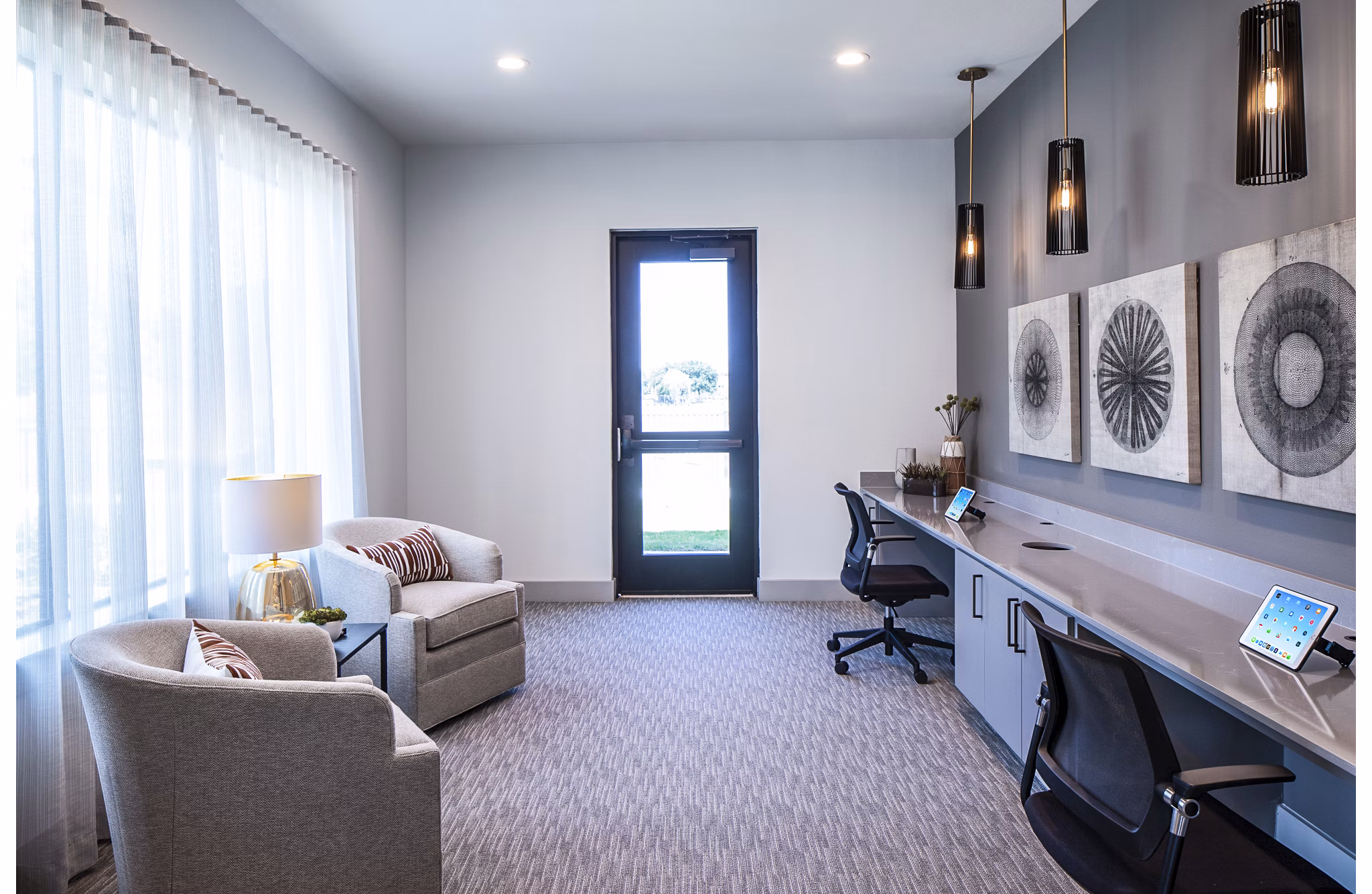 Modern office workspace with two chairs, long desk, wall art, and pendant lights