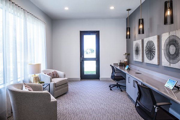 Modern office workspace with two chairs, long desk, wall art, and pendant lights