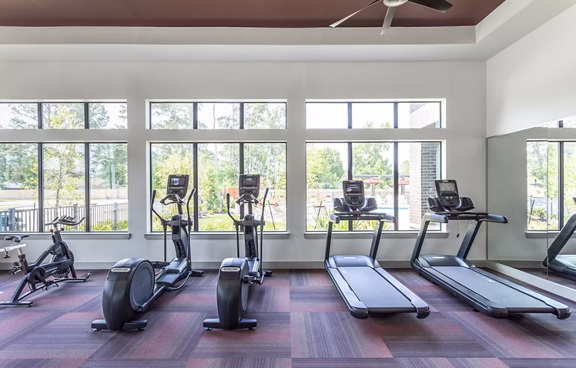Fitness center featuring treadmills and elliptical machines with large windows at luxury apartments
