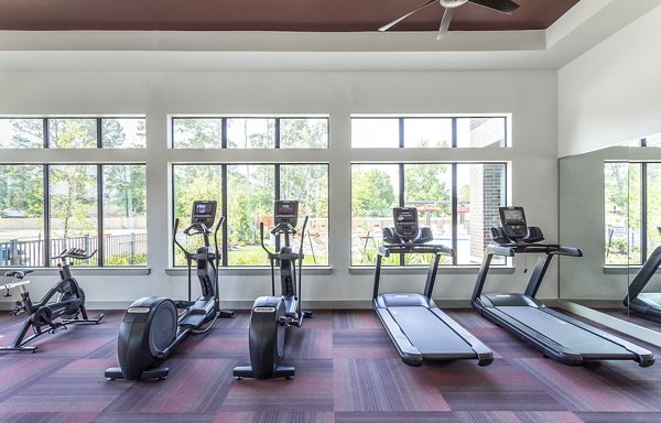 Fitness center featuring treadmills and elliptical machines with large windows at luxury apartments