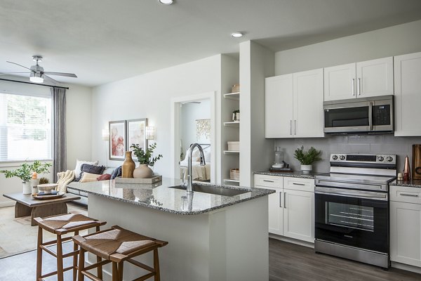 Modern kitchen and living area with white cabinets and granite island in luxury apartment Cozy seating area with sofa and wall art