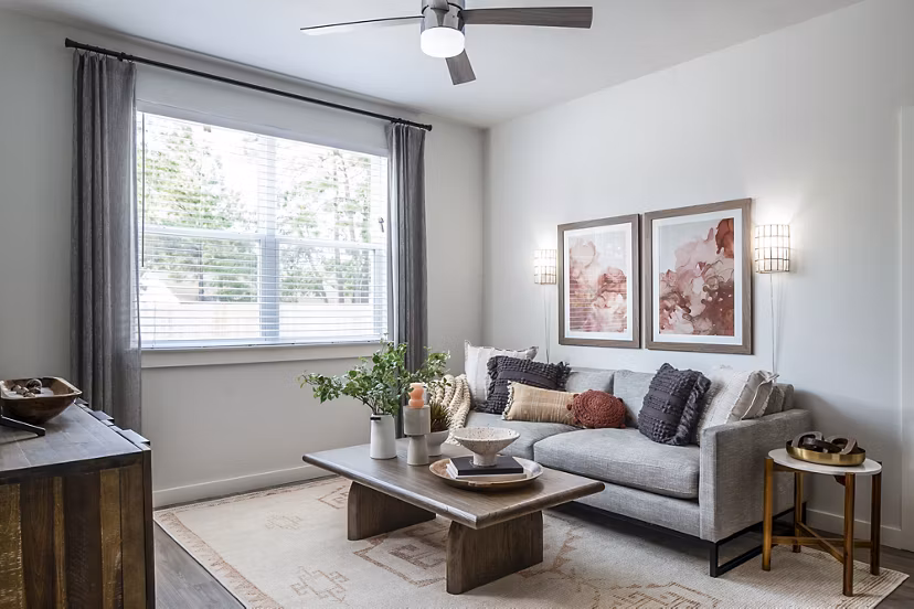 Modern living room featuring a stylish sofa, coffee table, wall art, and ceiling fan in luxury apartments