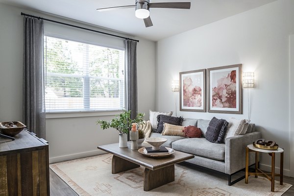 Modern living room featuring a stylish sofa, coffee table, wall art, and ceiling fan in luxury apartments
