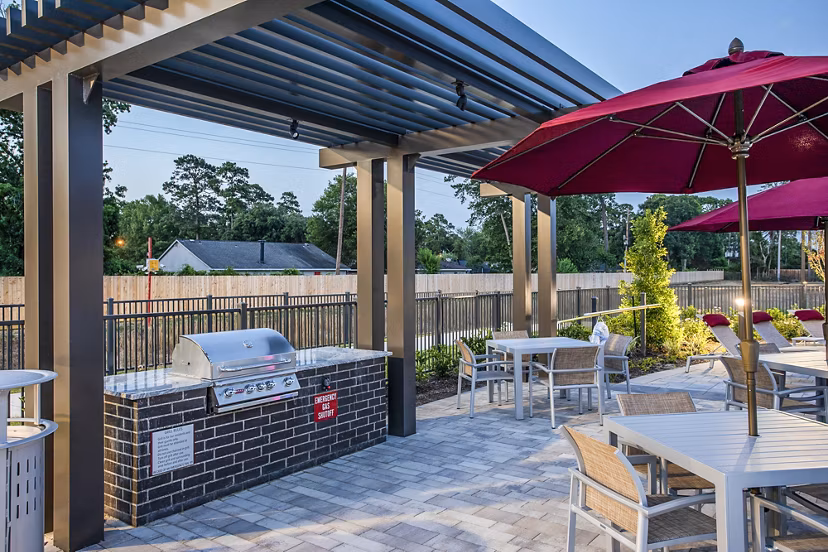 Outdoor patio area with tables, chairs, and a grill at luxury apartments, perfect for hosting gatherings