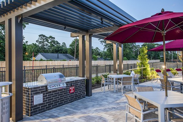 Outdoor patio area with tables, chairs, and a grill at luxury apartments, perfect for hosting gatherings