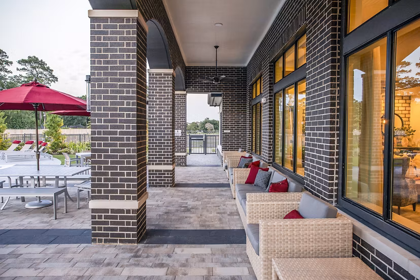 Inviting outdoor patio with brick columns and wicker seating at luxury apartments