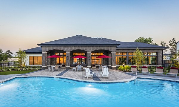Luxury swimming pool with outdoor seating and red umbrellas at Greystar luxury apartments