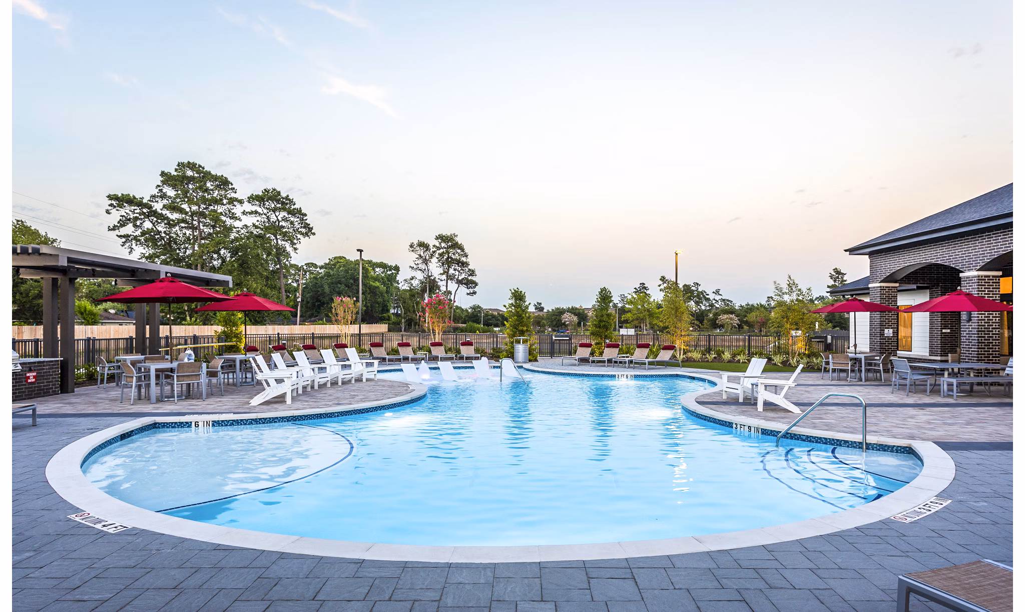 Inviting outdoor swimming pool area with lounge chairs and red umbrella tables at luxury apartments
