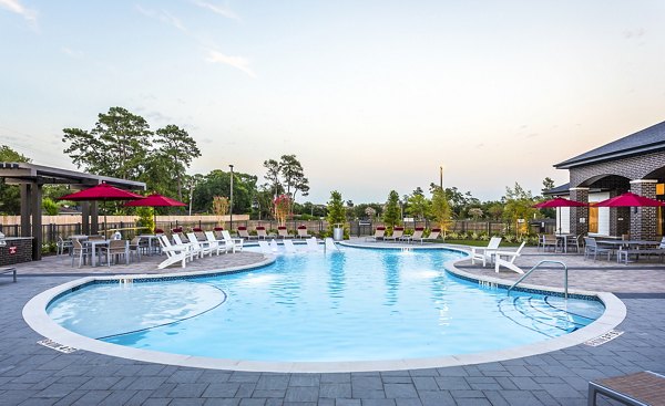 Inviting outdoor swimming pool area with lounge chairs and red umbrella tables at luxury apartments