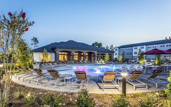 Resort-style swimming pool area with lounge chairs and lush landscaping at luxury apartments