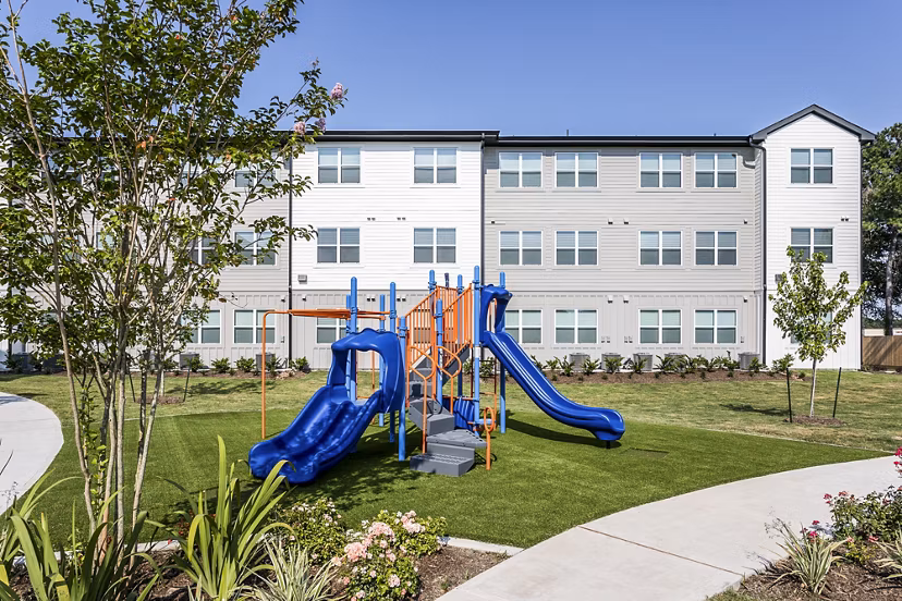Playground with blue slides and climbing equipment at luxury apartments