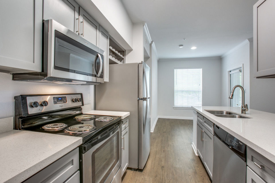 Modern kitchen with stainless steel appliances and granite countertops in Oak Crest Apartments