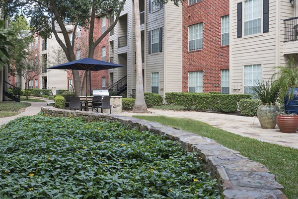 Tranquil courtyard with lush greenery at Woodland Park Apartments featuring shaded seating areas and walking paths