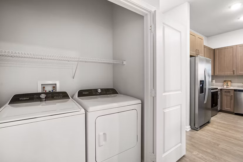 Laundry room with modern appliances and ample storage at Sanctuary at Daytona Apartments