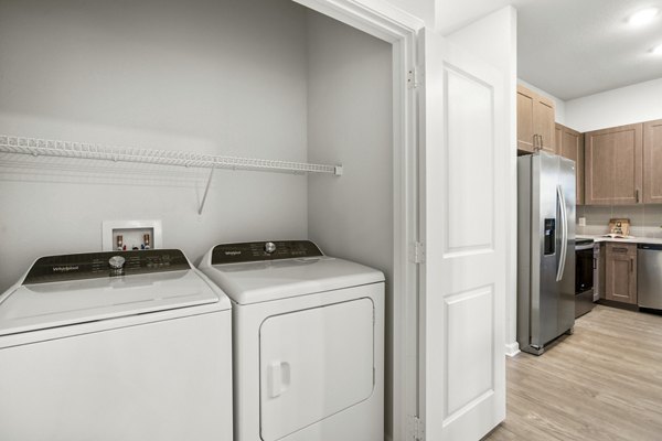 Laundry room with modern appliances and ample storage at Sanctuary at Daytona Apartments