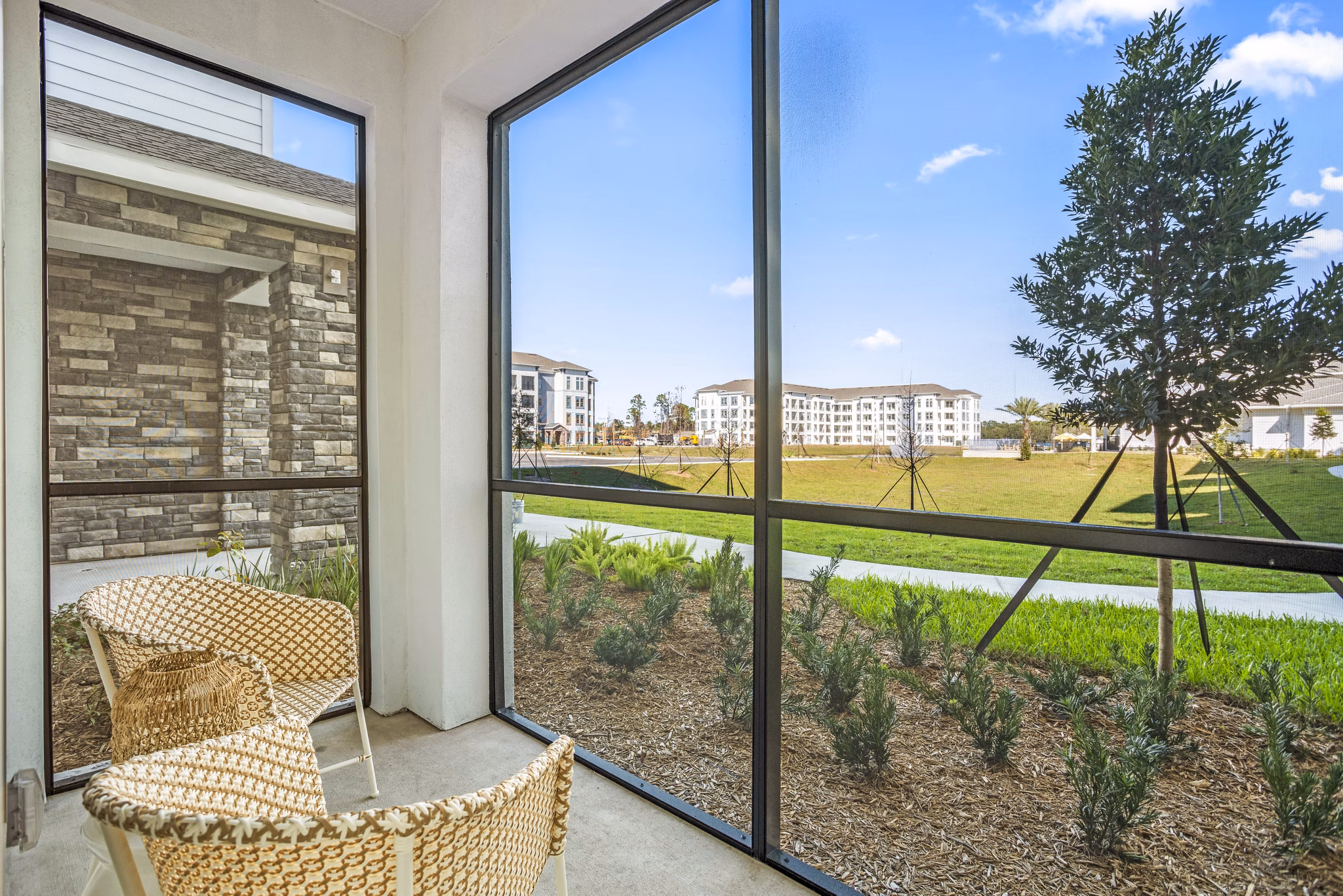 Patio with cozy seating and lush greenery at Sanctuary at Daytona Apartments, offering luxury living in a serene setting