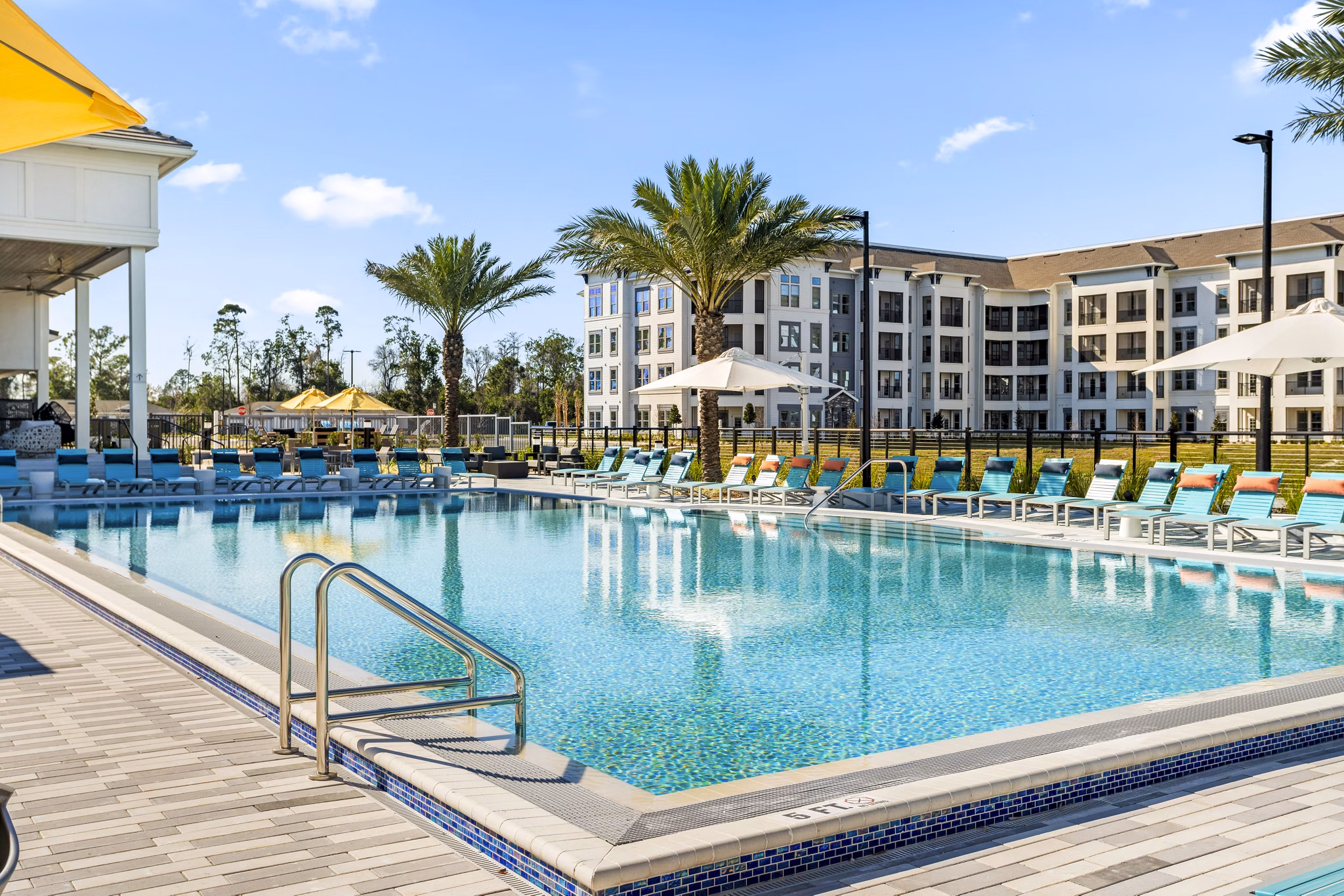 Resort-style pool at Sanctuary at Daytona Apartments with sun loungers and palm trees