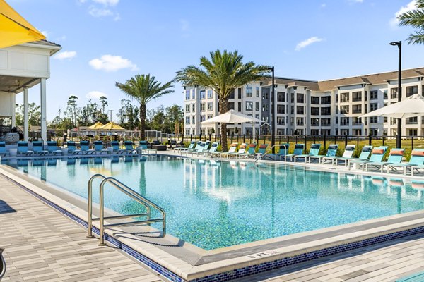 Resort-style pool at Sanctuary at Daytona Apartments with sun loungers and palm trees