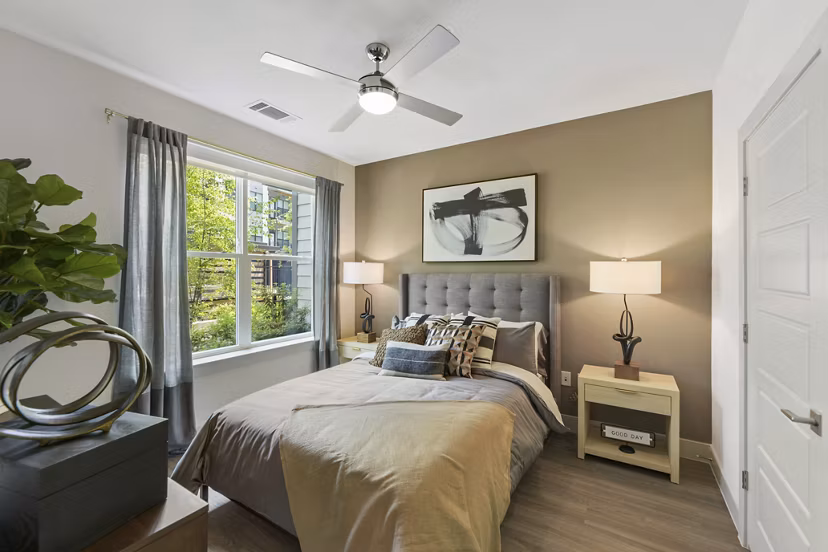 Cozy bedroom with modern decor at The Ian Apartments, featuring plush bedding and ample natural light