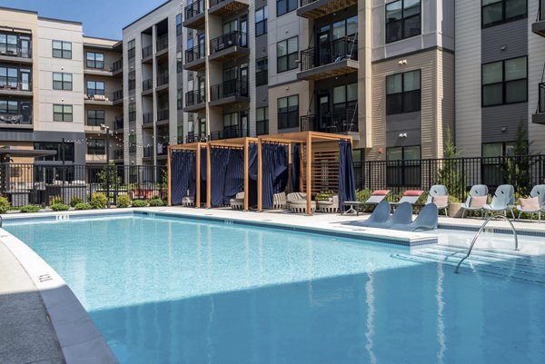Resort-style pool at The Ian Apartments with sun loungers and landscaped surroundings, offering luxury relaxation and leisure amenities