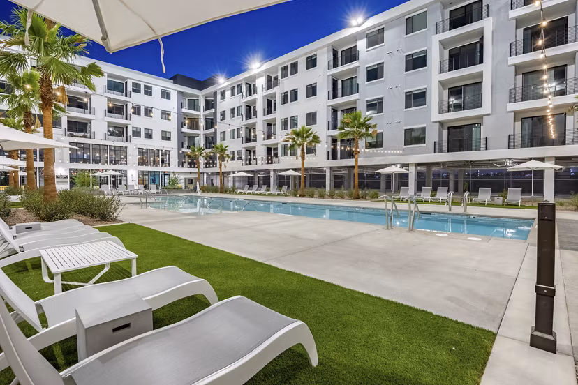 Pool amenity with lounge chairs and water features at theApex @ Meadows Apartments for luxury relaxation adjacent to residential living spaces
