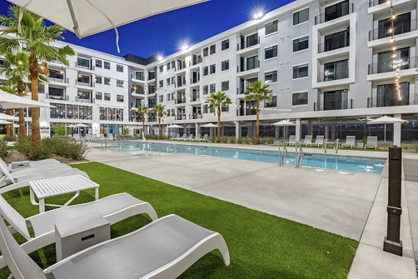 Pool amenity with lounge chairs and water features at theApex @ Meadows Apartments for luxury relaxation adjacent to residential living spaces
