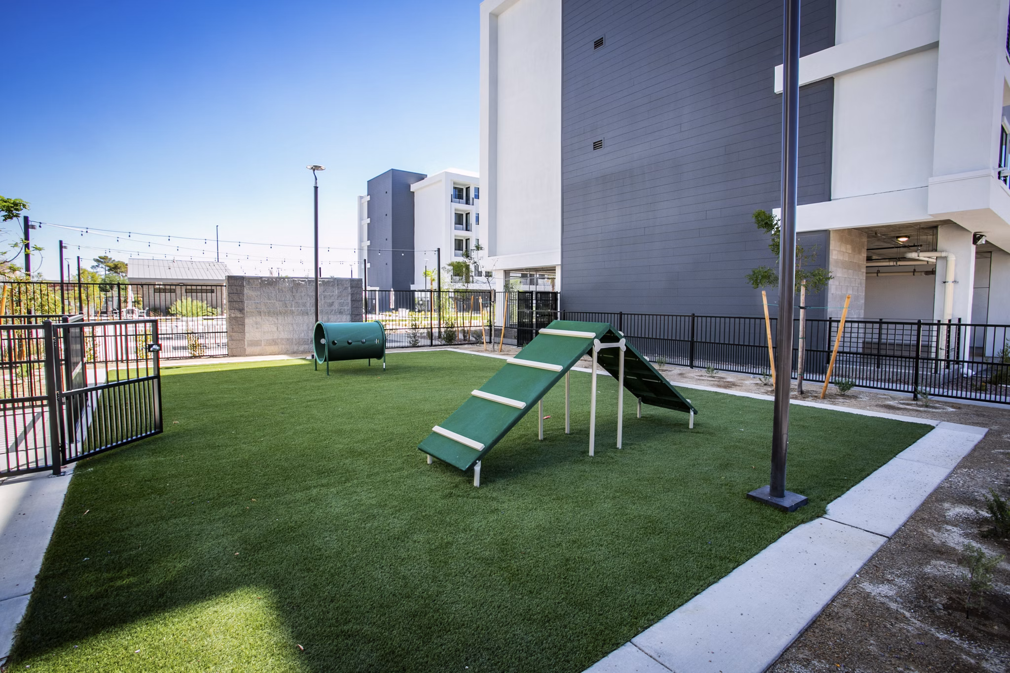 Modern dog park at TheApex @ Meadows Apartments with agility equipment and seating areas for resident pet owners
