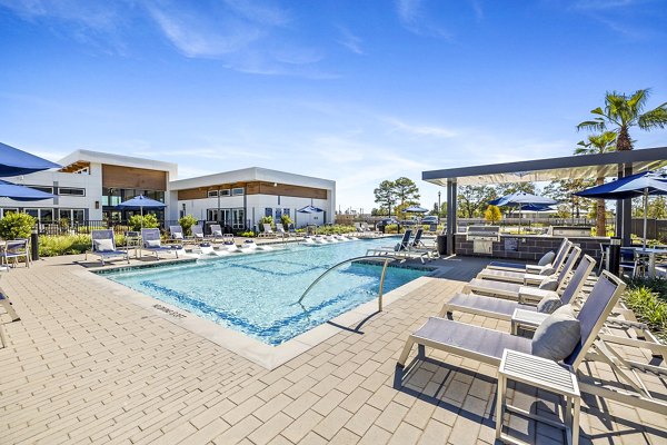 Poolside relaxation area at Birchway Spring Cypress Apartments featuring sleek loungers and landscaped surroundings