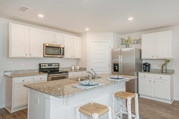 Kitchen featuring modern appliances and granite countertops at Sunset Village Apartments