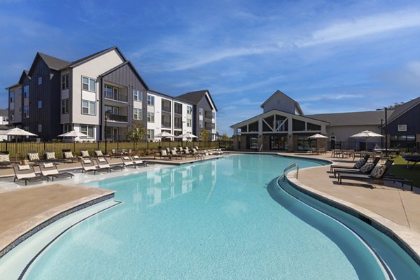 Modern swimming pool at Elan Brookwood Apartments featuring lounging areas and lush landscaping