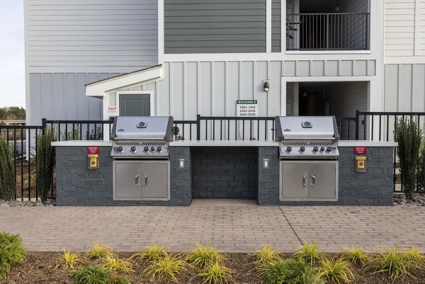 Outdoor grill area with modern seating and landscaping at Prose Rhyne Apartments, perfect for gatherings and socializing