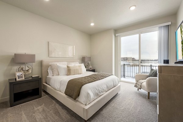 Cozy bedroom featuring plush bedding and natural light at H2O Townhomes Apartments, a luxury property offering by Greystar