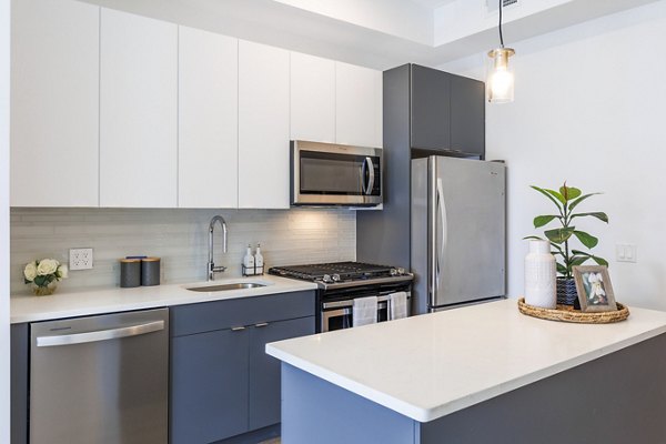 Modern kitchen featuring stainless steel appliances and marble countertops at The Bedford Apartments