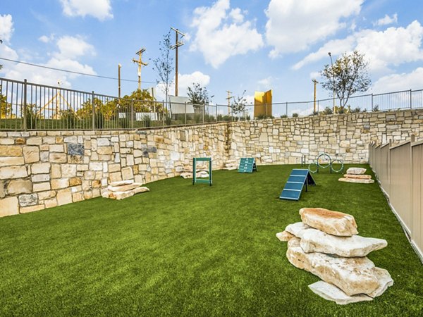 Spacious fenced dog park at Vecina Apartment Villas with green lawns and play area for residentsâ€™ pets