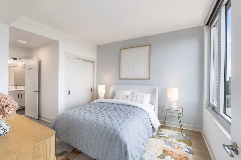 Elegant bedroom featuring modern decor and ample natural light at The Commodore Apartments