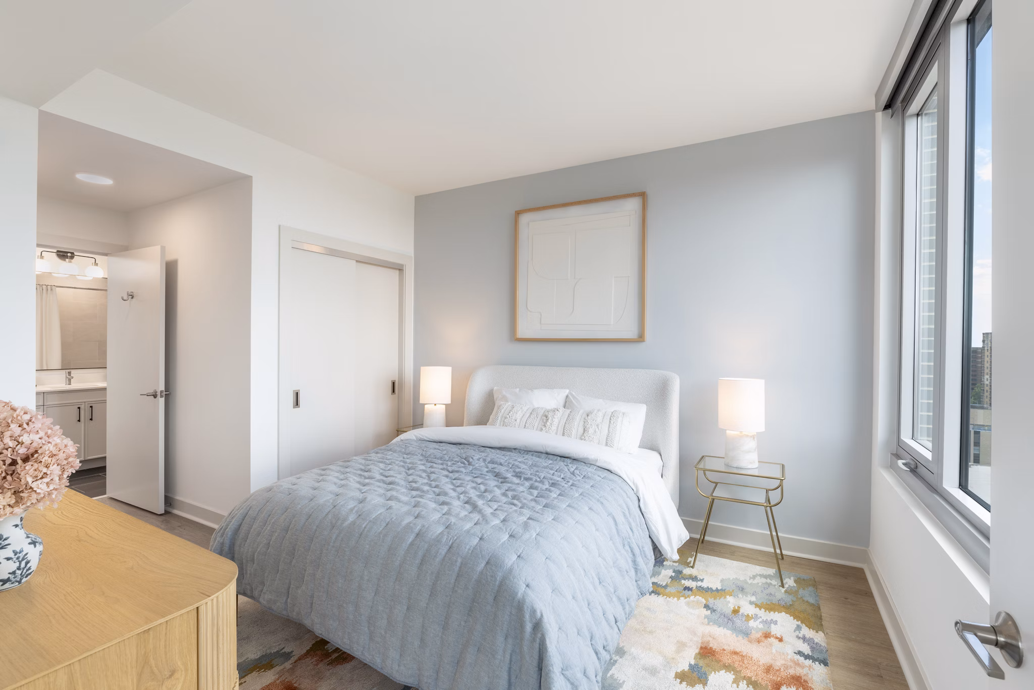 Elegant bedroom featuring modern decor and ample natural light at The Commodore Apartments
