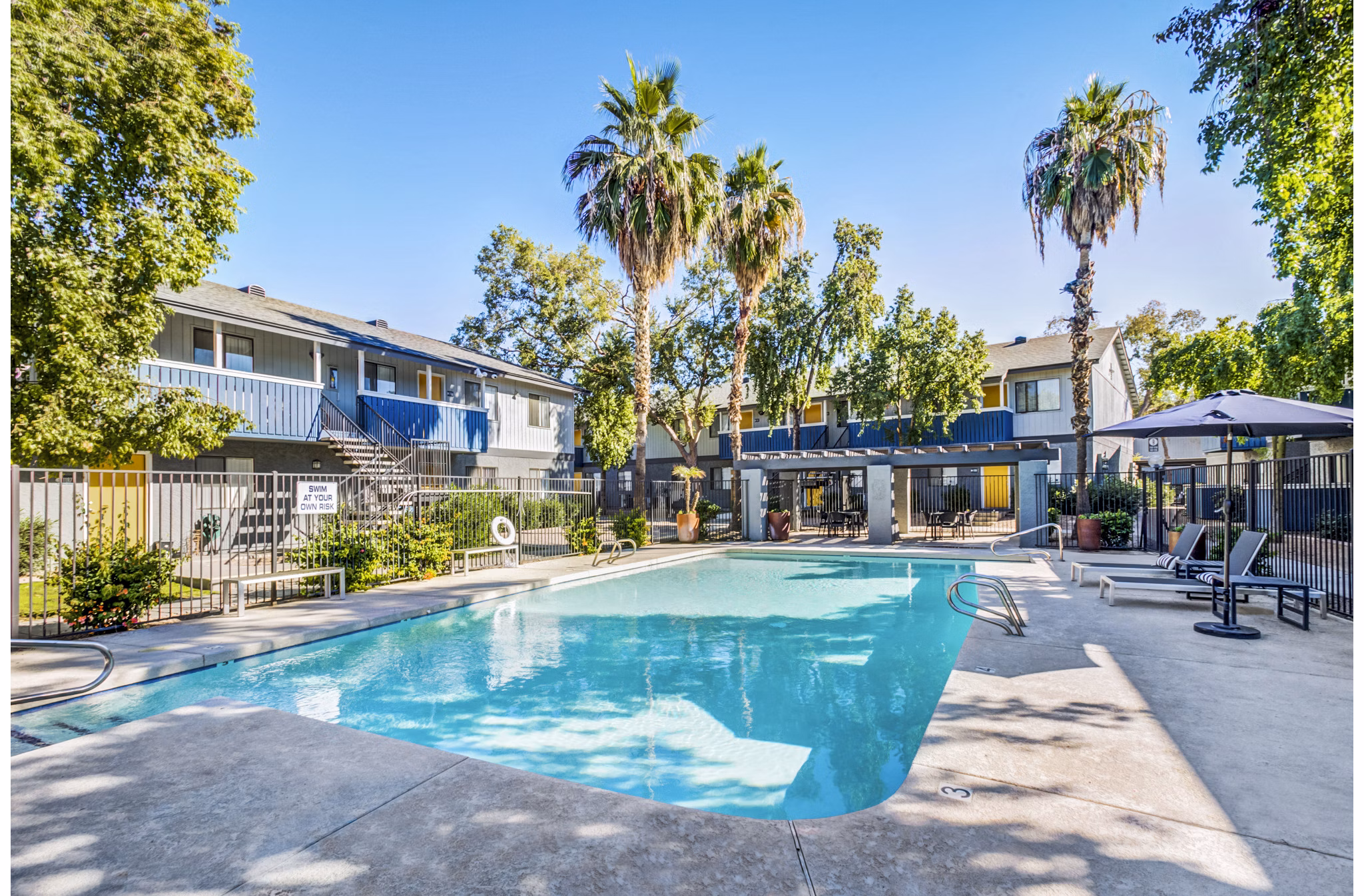 Outdoor swimming pool with lounging area at Monterey Village Apartments, offering luxury living experience