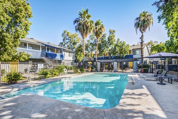 Outdoor swimming pool with lounging area at Monterey Village Apartments, offering luxury living experience