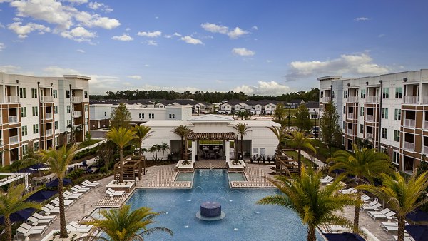 Spacious outdoor pool area at Aspire at Silverleaf Apartments featuring lush landscaping and modern lounge chairs for relaxation