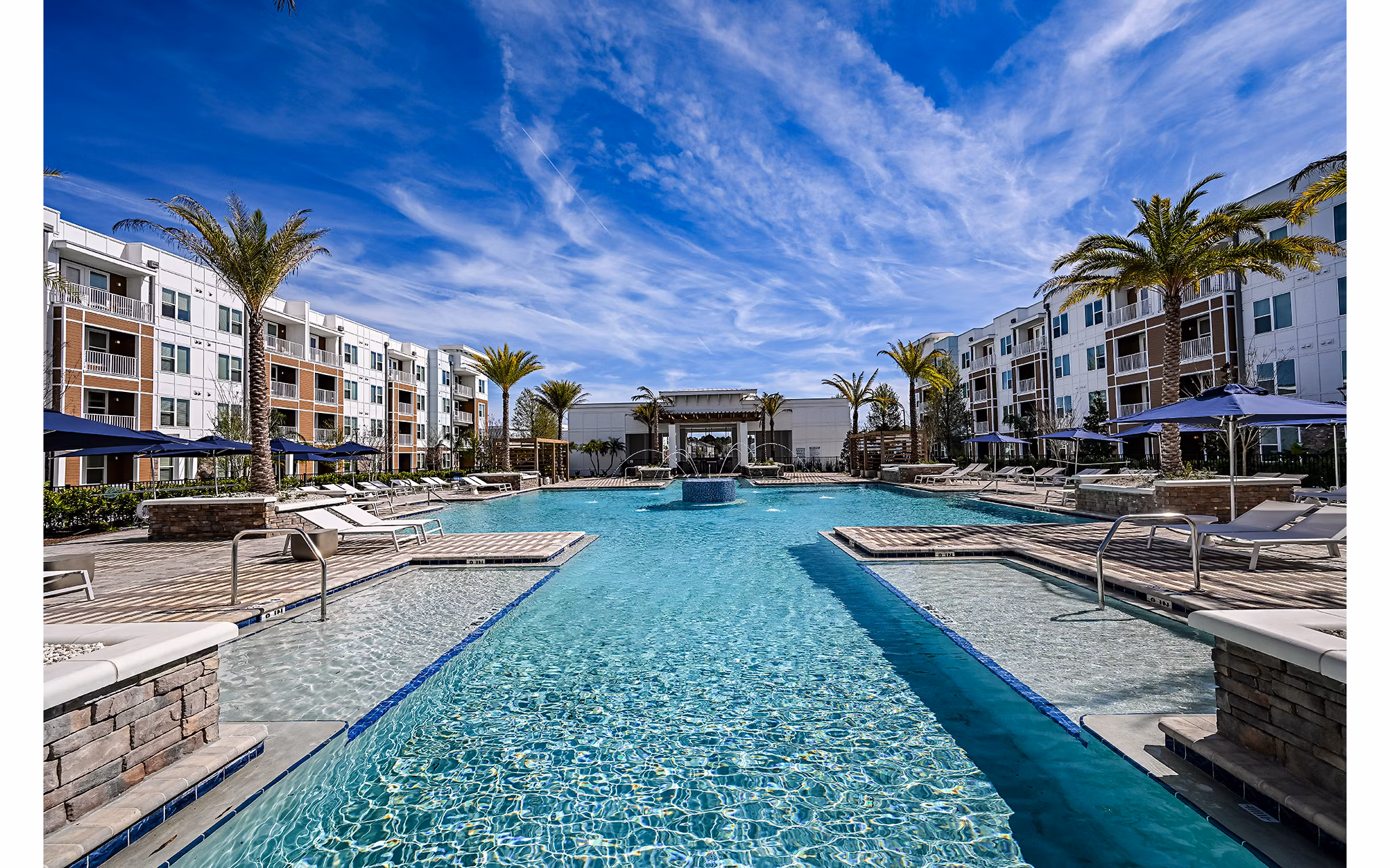 Modern pool area with lounge chairs and lush landscaping at Aspire at Silverleaf luxury apartments