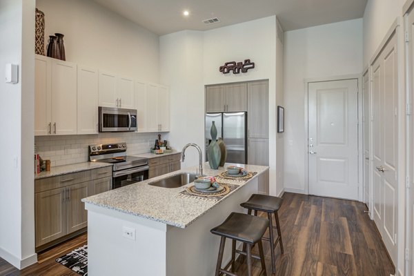 Modern kitchen featuring stainless steel appliances and sleek countertops in Prose Prominence Apartments