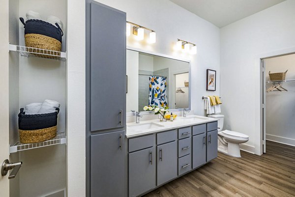 Elegant bathroom with marble countertops and glass shower at Legacy Encore Apartments
