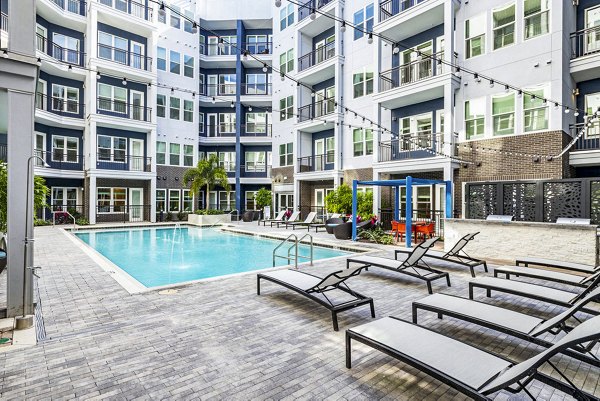 Luxurious poolside retreat at Legacy Encore Apartments with modern seating and lush landscaping