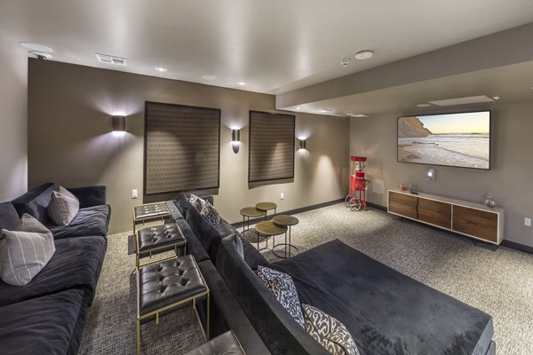 Clubhouse theater featuring plush seating and large screen at Aliso Apartments