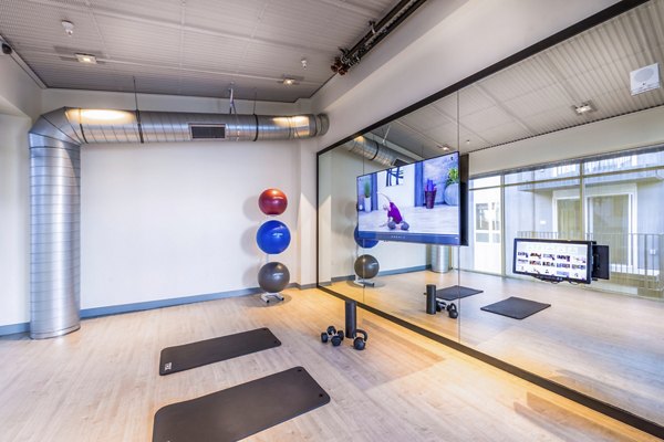 Yoga studio with mirrored walls and wood floors at Aliso Apartments