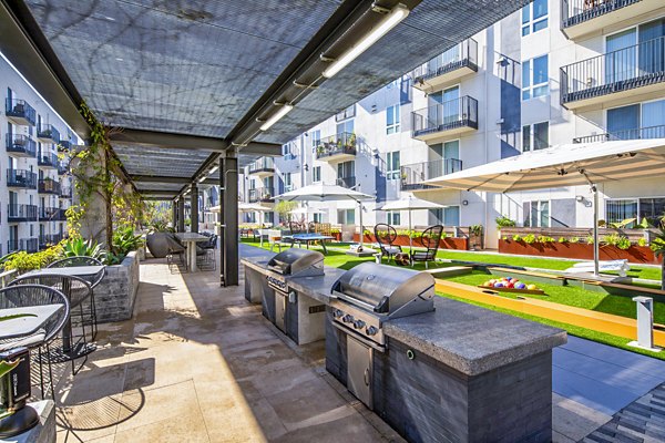 Outdoor grill area with modern patio furniture at Aliso Apartments, perfect for social gatherings and leisure moments