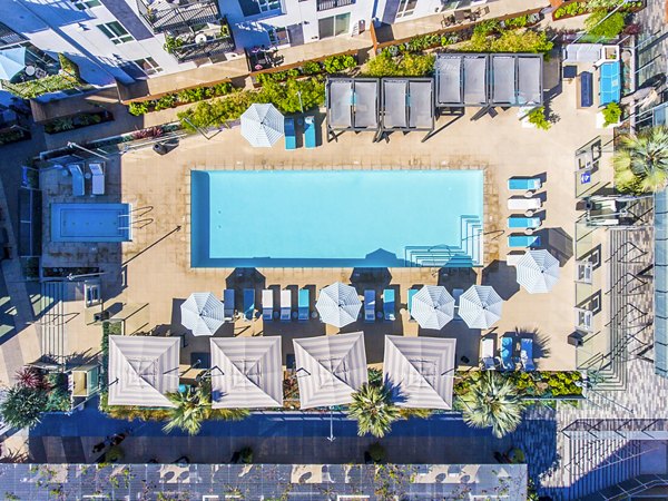 Outdoor pool with lounge chairs at Aliso Apartments, offering luxury living and relaxation in a Greystar community