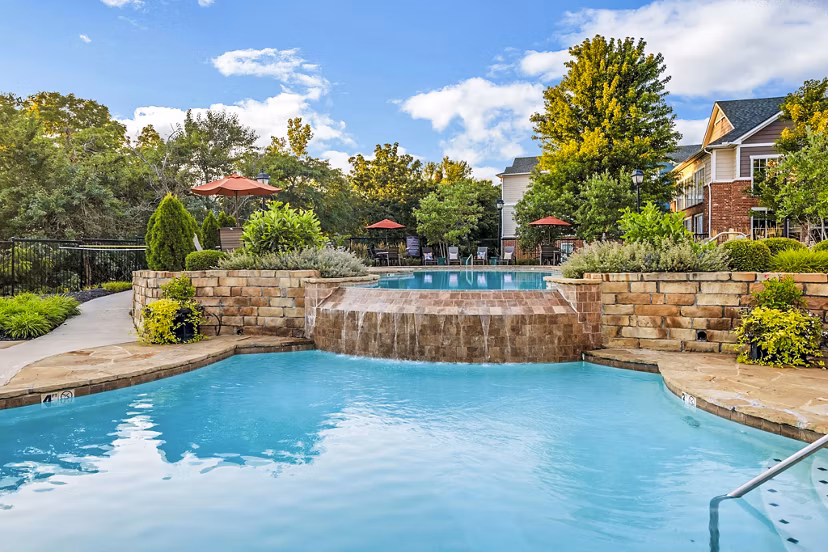 Resort-style pool at Aventura Clear Creek Apartments, featuring sun loungers and lush landscaping for luxury relaxation