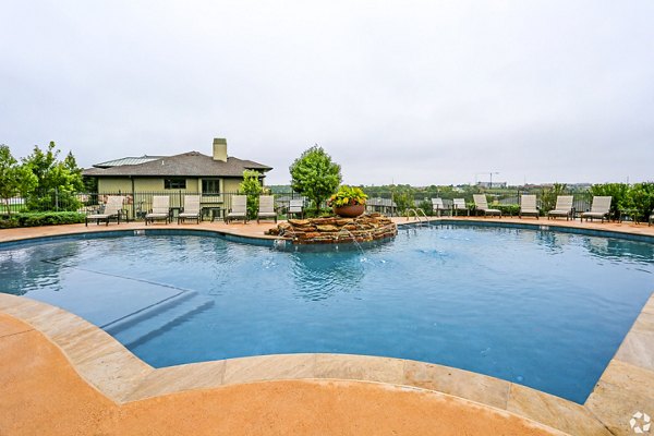 Resort-style pool at Aventura Falcon Valley Apartments with lounge seating and umbrellas