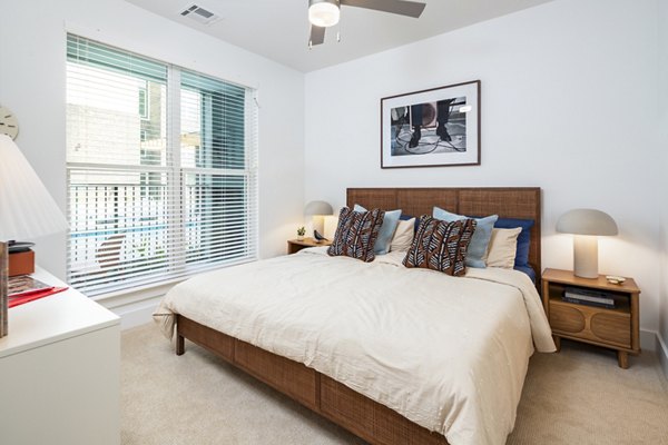 Stylish bedroom with modern decor at Rye Charlotte Ave Apartments featuring cozy bedding and ample natural light